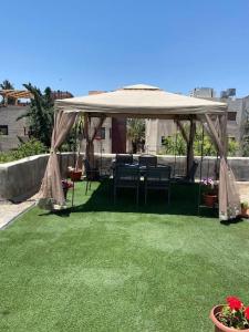 een tuinhuisje met stoelen en een tafel op het gras bij sunny 2bedroom apartment in weibdeh with a rooftop in Amman