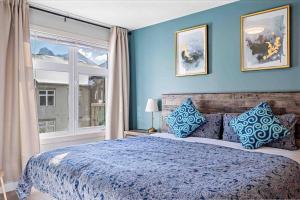 a blue bedroom with a large bed and a window at Lux 2BR 5BD Suite Mountain view! in Canmore