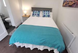 1 dormitorio con 1 cama grande con almohadas azules y blancas en The Snug, en Letterkenny