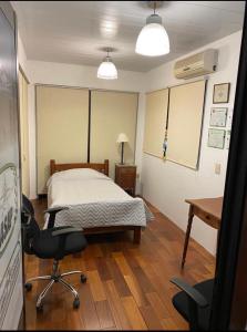 1 dormitorio con cama, escritorio y silla en ONE TRIP, en Paysandú