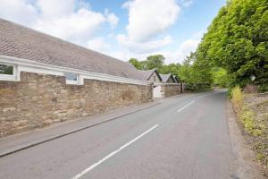 une route vide à côté d'un bâtiment en pierre dans l'établissement Two Bedroom Country Cottage With Parking, à Musselburgh