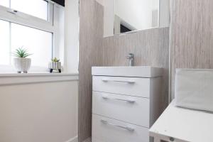 a white bathroom with a sink and a window at Two Bedroom Country Cottage With Parking in Musselburgh
