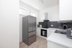 a kitchen with a stainless steel refrigerator and white cabinets at Two Bedroom Country Cottage With Parking in Musselburgh
