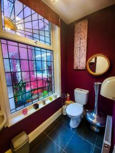 ein Bad mit einem WC und einem Buntglasfenster in der Unterkunft Hotel LUX (Rouge) in Blackpool