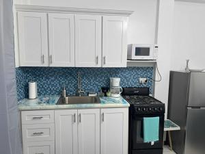 a kitchen with white cabinets and a sink and a stove at Chalet Belizomi Tropical Villas No #2 in Rodney Bay Village