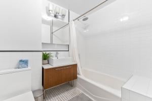 a white bathroom with a sink and a tub at Unique 3BR in NYC in New York