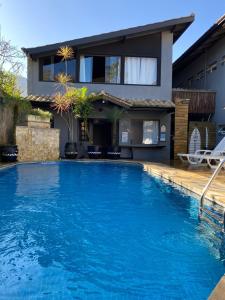 a house with a swimming pool in front of a house at Maré Leve Maresias in Maresias