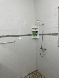 a shower in a white tiled bathroom at Dar El Amel in Mellita