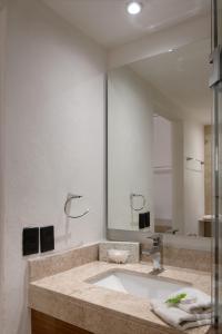 baño con lavabo y espejo grande en Hotel Calypso Cancun, en Cancún