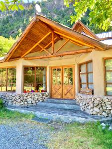 een huis met een houten deur en een stenen muur bij Hostería de Montaña Las Pataguas in El Hoyo