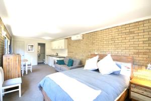 a bedroom with a bed and a brick wall at The Views - 3 or 4 Bedroom in Tura Beach
