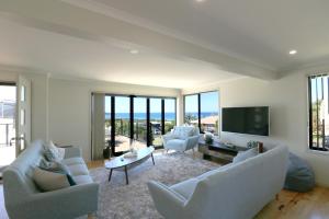 ein Wohnzimmer mit einem Sofa, Stühlen und einem TV in der Unterkunft The Views - 3 or 4 Bedroom in Tura Beach