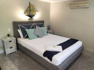 a bedroom with a bed with blue and white pillows at Wildferns Lodge and Sailors Studio Opua in Opua