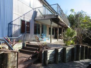 a house with a balcony and stairs leading to it at Wildferns Lodge and Sailors Studio Opua in Opua