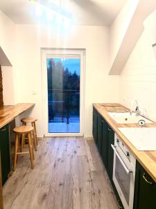 a kitchen with green cabinets and a large window at Apartamenty na Wzgórzu Boho in Zagnańsk