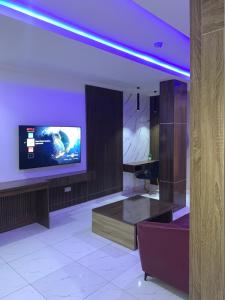 a room with a tv on a wall with a table at Executive Royal Suite Kado in Abuja