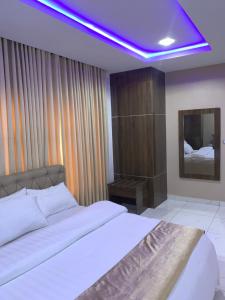 um quarto com uma cama branca e um tecto roxo em Executive Royal Suite Kado em Abuja