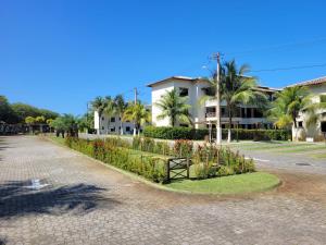 eine Straße vor einem Gebäude mit Palmen in der Unterkunft Genipabu Club House Guarajuba Camaçari-Ba in Camaçari