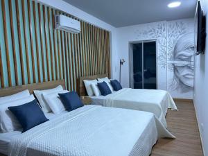 Roldanillo的住宿－Hotel Cocli，酒店客房设有两张床,墙上挂有绘画作品