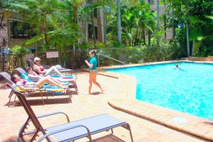 a group of people sitting in chairs by a swimming pool at Sea Point Ocean Apartments in Caloundra