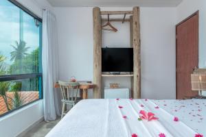 a bedroom with a bed and a large window at Vila Anauá in Japaratinga