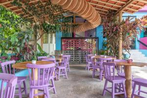 a restaurant with purple tables and chairs and plants at Vila Anauá in Japaratinga