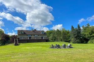 ein Haus auf einem Feld mit Stühlen im Gras in der Unterkunft Spacious Hammondsport Home on 6 Acres with Lake View in Hammondsport
