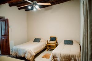 a bedroom with two beds and a ceiling fan at Huaco Casa de Campo in Belén