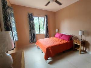 um quarto com uma cama com almofadas cor-de-rosa e uma janela em Casa Aguila em San Juan del Sur