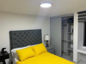 1 dormitorio con cama amarilla y cabecero gris en Cozy Wine Pedregal en Ciudad de México
