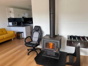 a living room with a chair and a stove at Cosy Tin Shack - Venus Bay in Venus Bay