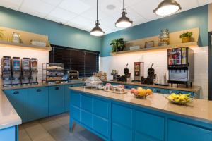 - une grande cuisine avec des placards bleus et des fruits sur le comptoir dans l'établissement Country Inn & Suites by Radisson, Wichita East, KS, à Wichita
