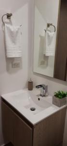 La salle de bains est pourvue d'un lavabo blanc et d'un miroir. dans l'établissement BV08 LUXESTUDIO, à Ibagué