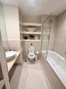 a bathroom with a toilet and a tub and a sink at NEW Two Bedroom Apartment with Balcony in London