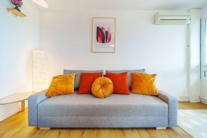 um sofá azul com almofadas laranja numa sala de estar em Charmant 2 chambres rénové avec balcon-Oullins em Oullins