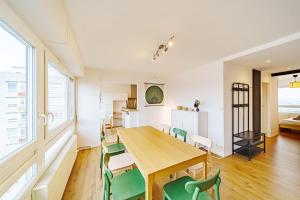 uma sala de jantar com uma mesa de madeira e cadeiras verdes em Charmant 2 chambres rénové avec balcon-Oullins em Oullins