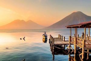 a boat in the water next to a dock with a bird at Unicorn Reborn - Peaceful Rentals in San Marcos La Laguna
