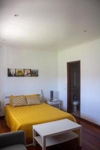 a bedroom with a yellow bed and a table at Quinta Casal da Eva in Alcobaça