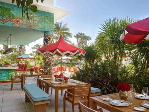 マイアミビーチにあるファエナ ホテル マイアミ ビーチの木製のテーブルと椅子、ヤシの木があるレストラン