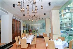 a dining room with white tables and chairs and a chandelier at Sky City Hotel Dhaka in Dhaka