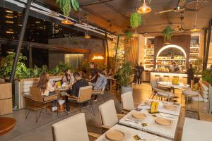 a group of people sitting at tables in a restaurant at 1616 Hotel in Medellín