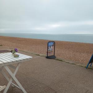 a picnic table next to a beach with a sign at Hideaway Cottage - Private ensuite room - 4 minutes to the sea! in Sandgate