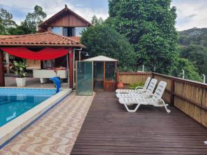 a deck with two white chairs and a swimming pool at Refúgio Bonanza in Teixeiras