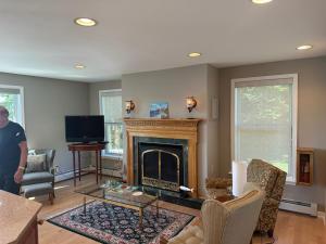 a man standing in a living room with a fireplace at Claddagh Cottage in Richfield Springs