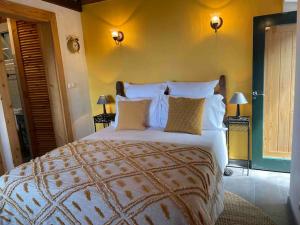 1 dormitorio con 1 cama grande con sábanas y almohadas blancas en Casa do Laureano, en Santo Amaro