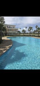 a large swimming pool with blue water in front of a building at Les perles de tamaris in Casablanca