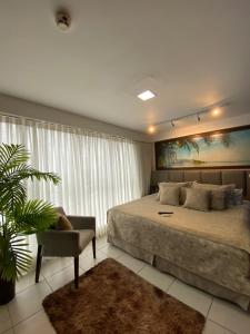 a bedroom with a large bed and a chair at Flat Executive Beira Mar in Recife