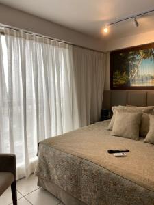 a bedroom with a bed and a large window at Flat Executive Beira Mar in Recife