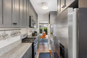 a kitchen with stainless steel appliances and a hallway at Craftsman Bungalow- University Heights 2BR Home in San Diego