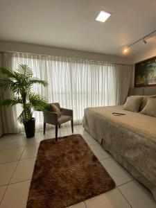a bedroom with a bed and a chair and a plant at Flat Executive Beira Mar in Recife